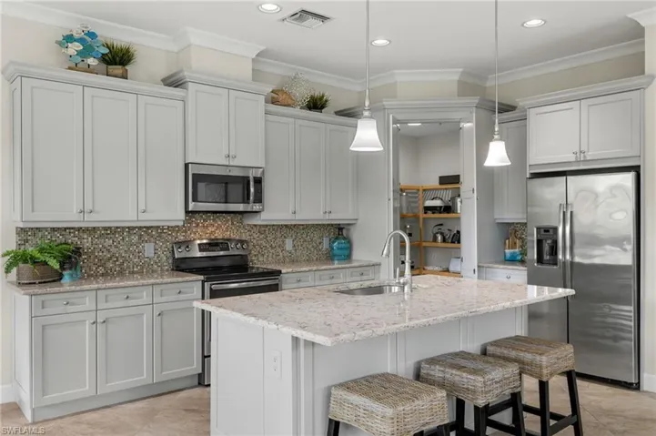 Kitchen with backsplash, sink, appliances with stainless steel finishes, a kitchen island with sink, and light tile patterned floors