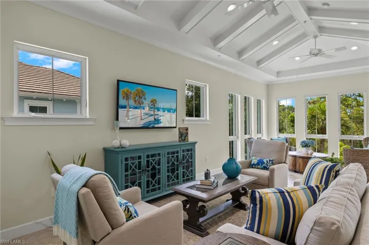 Living room with ceiling fan, plenty of natural light, and lofted ceiling with beams
