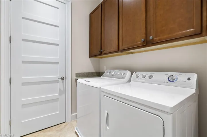 Laundry area featuring cabinets, separate washer and dryer, and light tile patterned floors