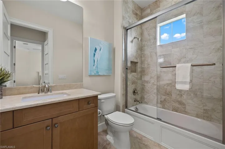 Full bathroom featuring tile patterned floors, enclosed tub / shower combo, vanity, and toilet