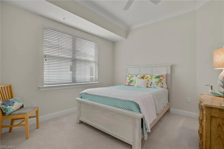 Carpeted bedroom with ceiling fan and ornamental molding