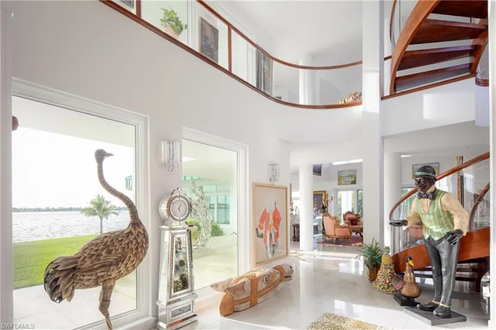 Tiled entrance foyer with a high ceiling, a water view, and stairs