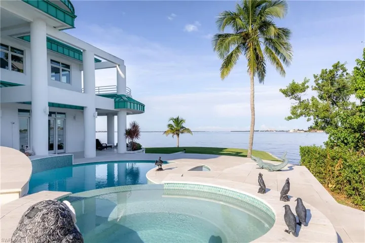 View of pool featuring a water view, a patio, french doors, and a pool with connected hot tub