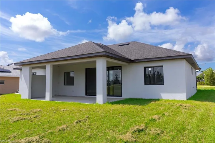 Rear view of house with a lawn and a patio