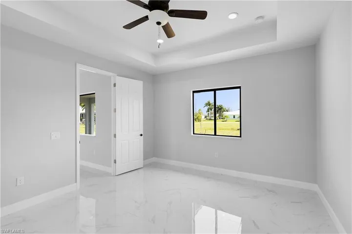 Spare room featuring ceiling fan, a raised ceiling, and light tile patterned floors