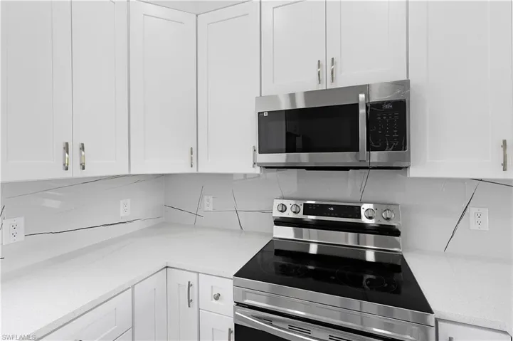 Kitchen with white cabinetry, appliances with stainless steel finishes, and backsplash