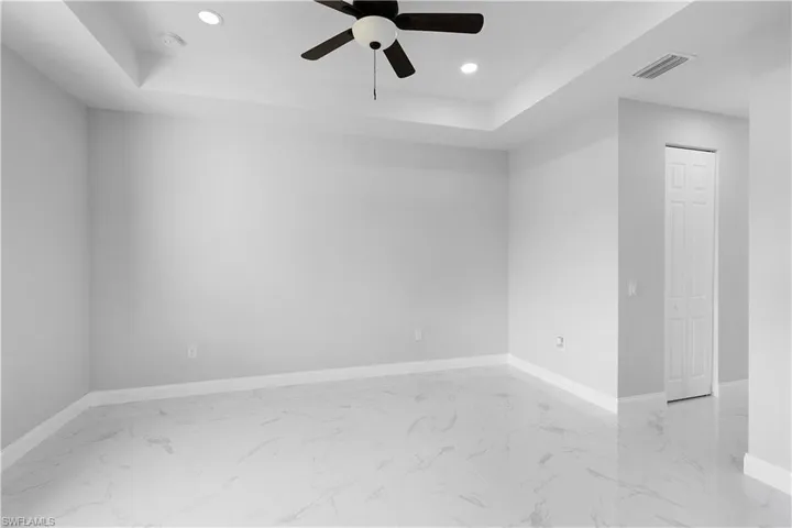 Tiled spare room with ceiling fan and a raised ceiling