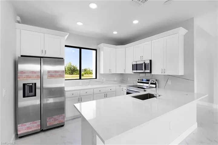 Kitchen with tasteful backsplash, white cabinetry, appliances with stainless steel finishes, and light tile patterned floors