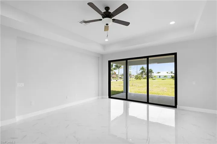 Tiled spare room featuring ceiling fan and a tray ceiling