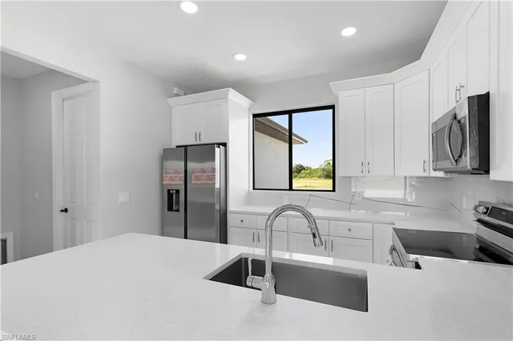 Kitchen featuring white cabinetry, sink, stainless steel appliances, and tasteful backsplash
