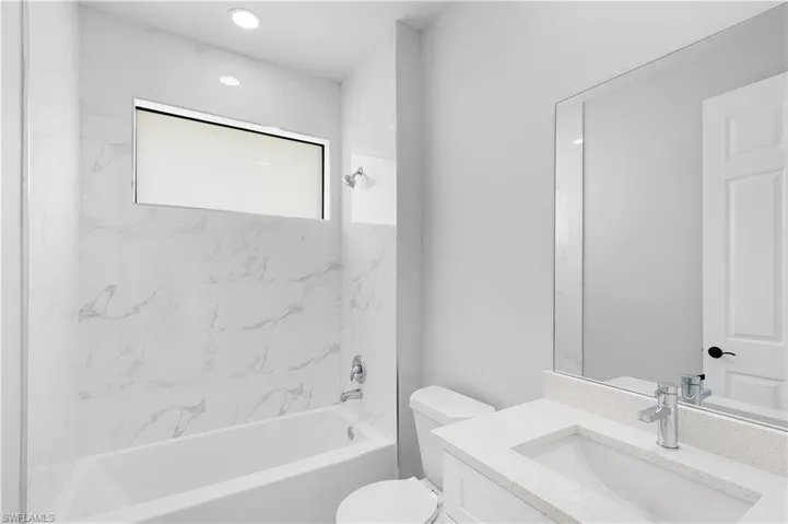 Full bathroom with vanity, tiled shower / bath combo, and toilet