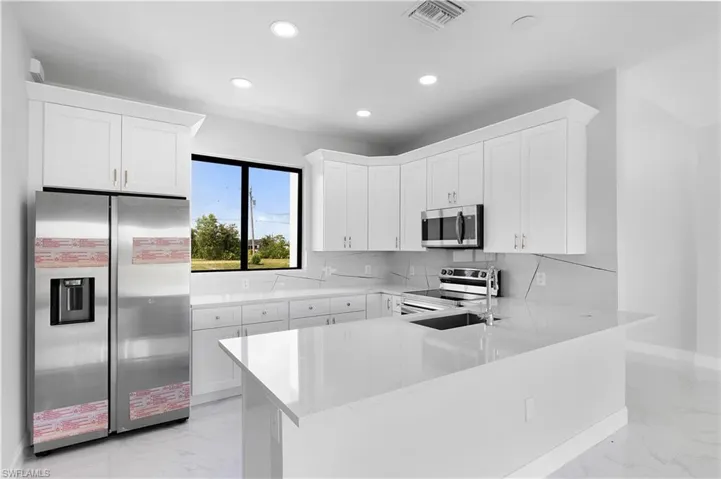 Kitchen featuring light tile patterned floors, stainless steel appliances, tasteful backsplash, and white cabinets