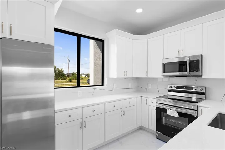 Kitchen featuring tasteful backsplash, white cabinetry, appliances with stainless steel finishes, and light tile patterned floors