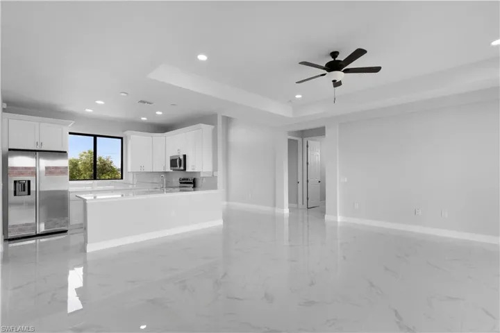 Kitchen featuring appliances with stainless steel finishes, a tray ceiling, white cabinetry, and light tile patterned floors