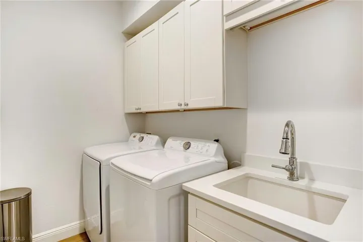 Laundry room featuring independent washer and dryer, sink, and cabinets