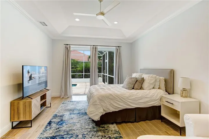 Bedroom with a raised ceiling, ceiling fan, access to exterior, and light hardwood / wood-style flooring