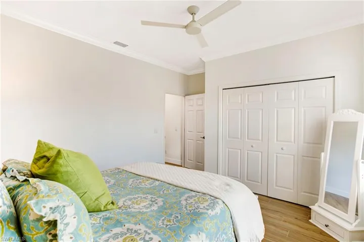 Bedroom featuring a closet, ceiling fan, light wood-type flooring, and ornamental molding