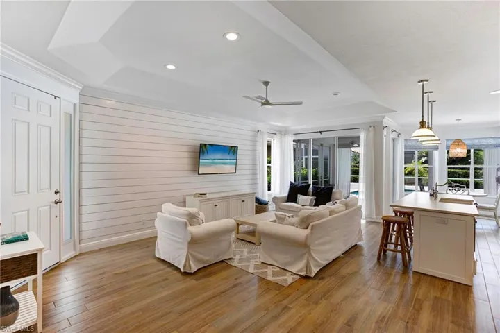 Living room with a raised ceiling, ceiling fan, light hardwood / wood-style floors, and a wealth of natural light