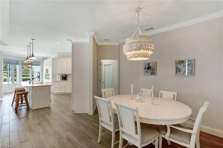 Dining area with sink, an inviting chandelier, ornamental molding, and light hardwood / wood-style flooring
