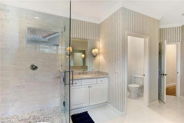 Bathroom with a shower with door, ornamental molding, vanity, and toilet
