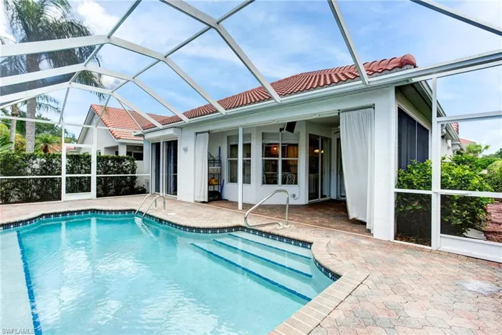 View of pool with a patio and glass enclosure