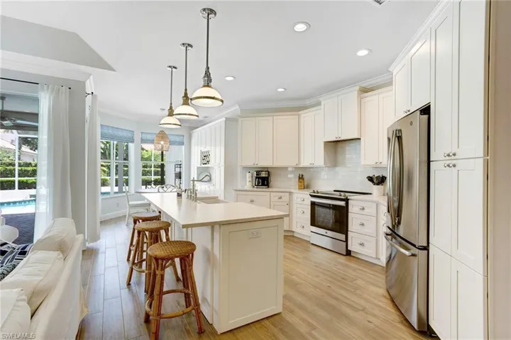 Kitchen with light hardwood / wood-style floors, backsplash, a center island with sink, appliances with stainless steel finishes, and sink