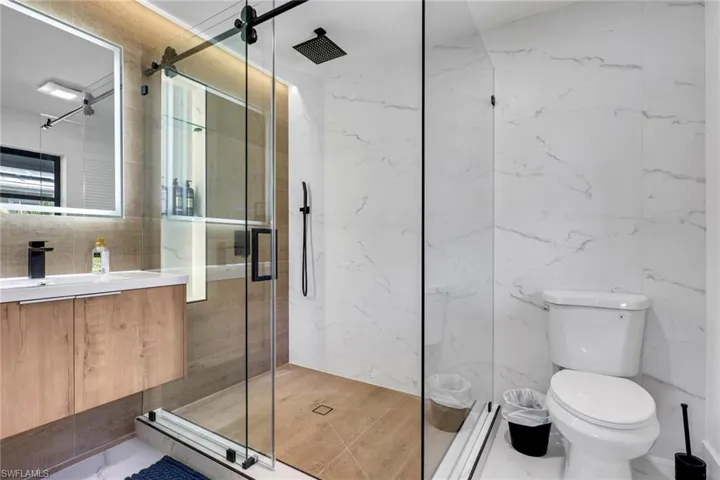 Bathroom featuring Bathroom-vanity, a marble finish shower, and tile walls