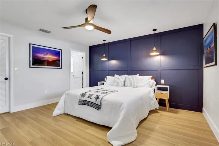 Bedroom 1- with a decorative wall, wood finished floors, a ceiling fan, and an accent wall