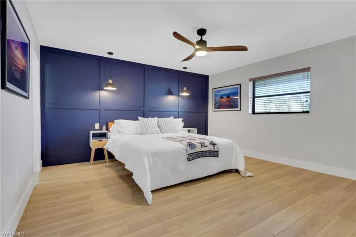 Bedroom 1- with a decorative wall, a ceiling fan, light wood-type flooring, and an accent wall