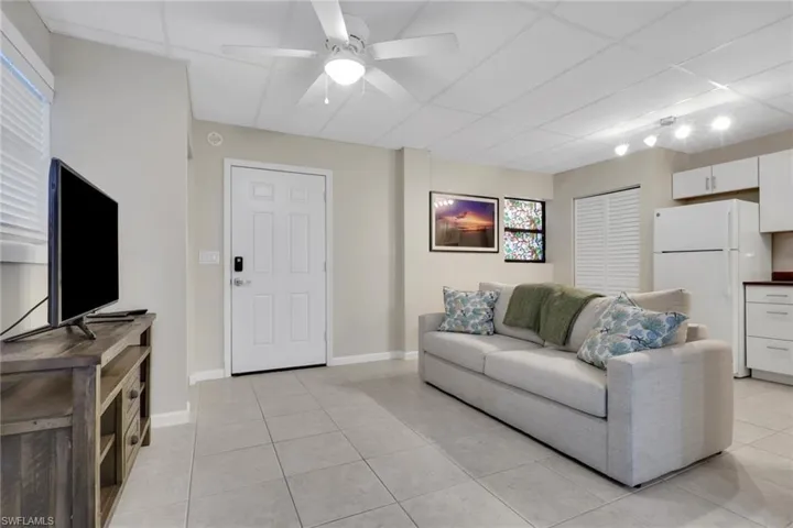 1/1 Efficiency-Living room with a paneled ceiling, light tile patterned flooring, and ceiling fan