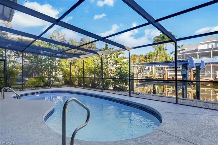 Outdoor pool featuring glass enclosure, a sunroom, and boat lift