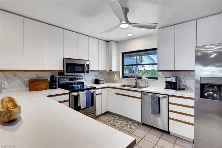 Kitchen with light countertops, stainless steel appliances, white cabinetry, light tile patterned floors, and recessed lighting