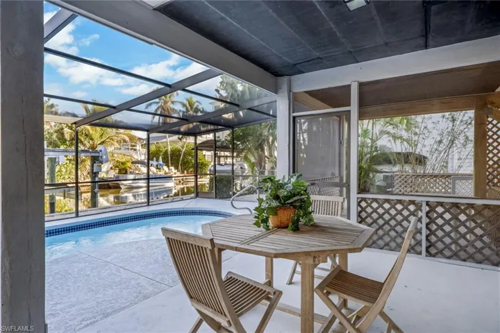 Outdoor pool featuring a patio, a sunroom, and glass enclosure