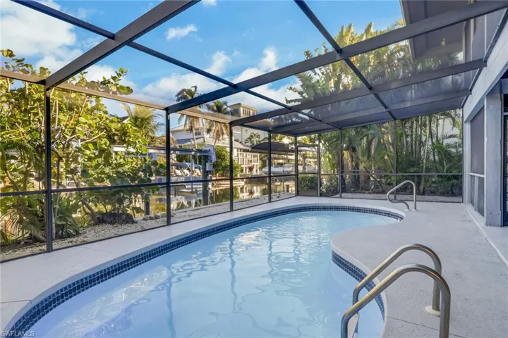 Outdoor pool featuring a sunroom, glass enclosure, and a patio
