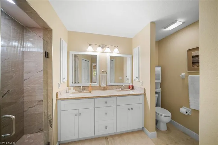 Primary bathroom with renovated glass shower door, upgraded lighting, and cabinets.