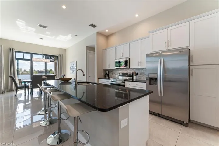 Kitchen featuring stainless steel appliances, a center island with sink, tasteful backsplash, a breakfast bar