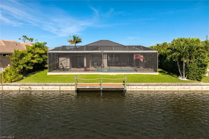 Rear view of property with a yard, a water view, an outdoor pool, and a patio area