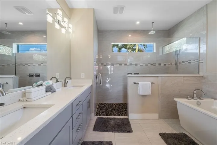 Bathroom with a walk in shower, double vanity, and a soaking tub