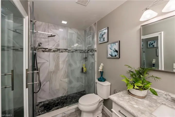 Bathroom with tile patterned flooring, toilet, vanity, and a shower with shower door