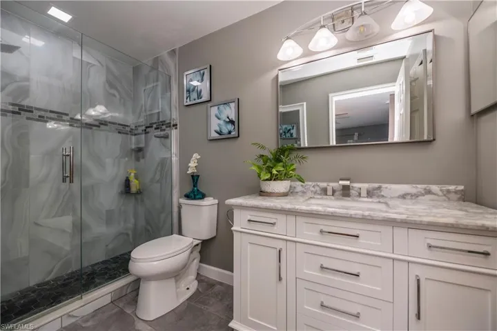 Bathroom featuring tile patterned flooring, a shower with door, toilet, and vanity