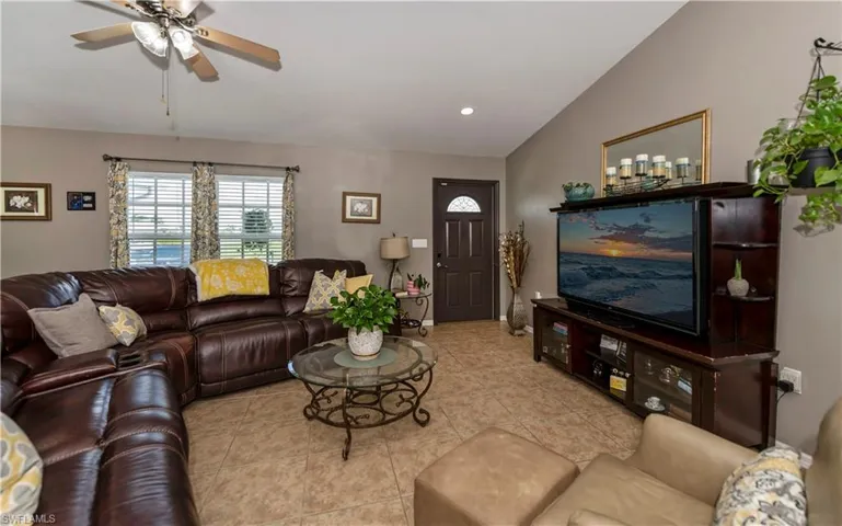 Tiled living room featuring ceiling fan and lofted ceiling