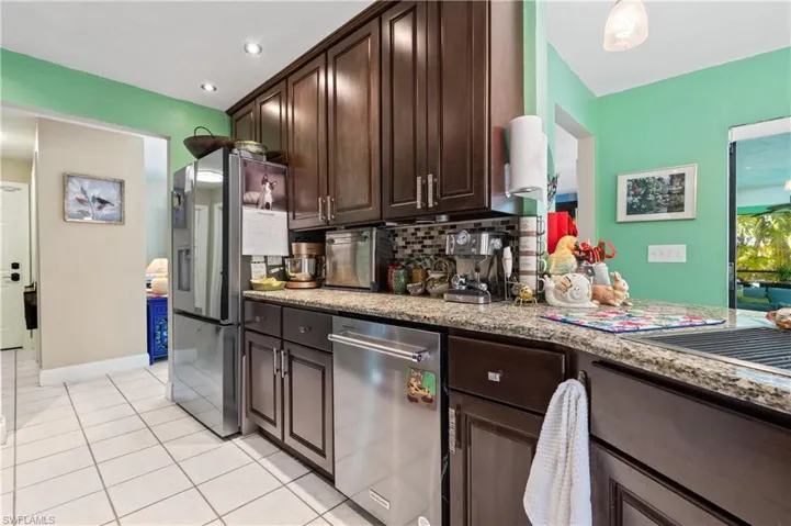View of Granite Kitchen with High End Stainless Appliances, Crown Molded Cabinetry to Ceiling [Note attractive Designer Cabinetry Hardware] w/Deep Stainless Farmhouse Sink with Rollback Drainboard, Pot Filler and Built In Soap Dispenser and Accessories.