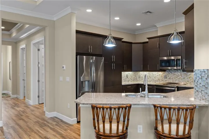 Kitchen featuring a breakfast bar, sink, decorative light fixtures, and appliances with stainless steel finishes