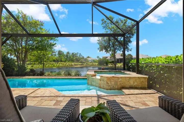 View of pool with raised spa featuring a covered lanai with water views.