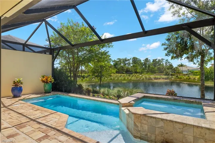 View of swimming pool with a lanai, an in ground hot tub, a patio area, and a water view