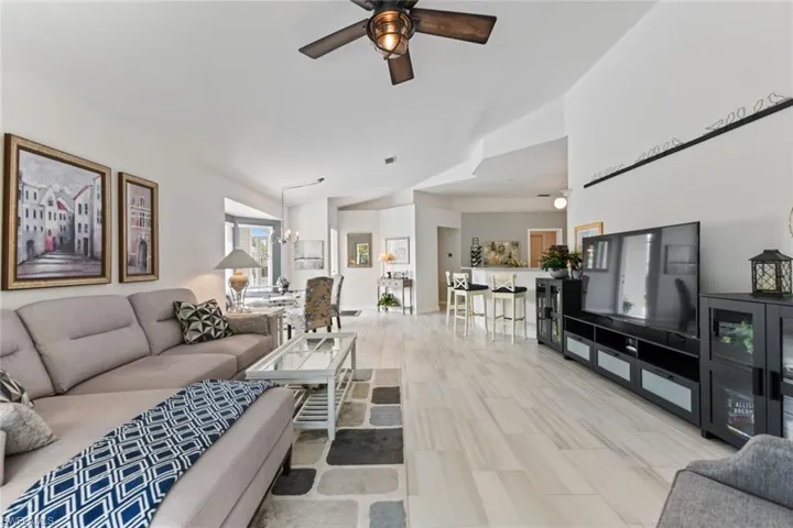 Living room with ceiling fan with notable chandelier and high vaulted ceiling