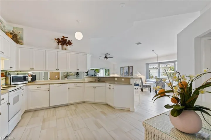 Kitchen with white appliances, decorative light fixtures, kitchen peninsula, and white cabinets