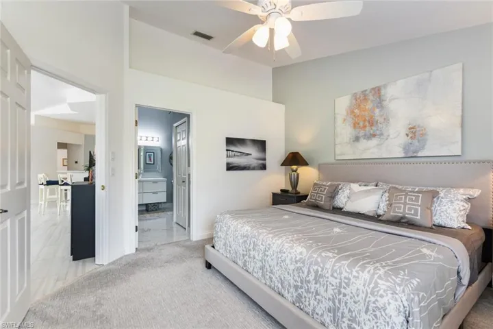 Carpeted bedroom with connected bathroom and ceiling fan