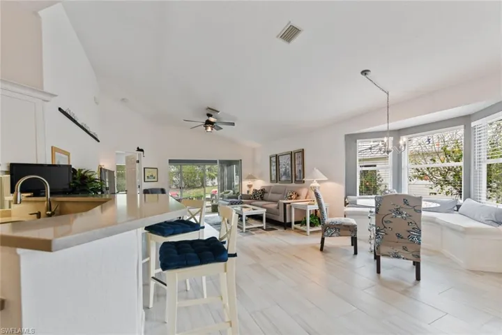Kitchen featuring sink, a breakfast bar, hanging light fixtures, high vaulted ceiling, and ceiling fan with notable chandelier