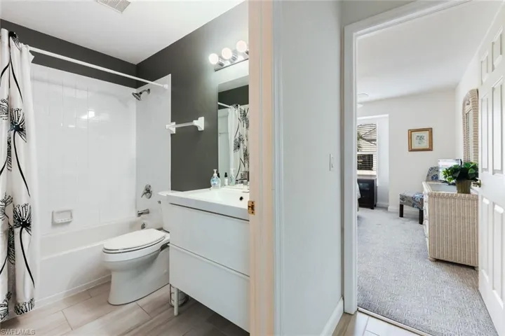 Full bathroom featuring vanity, shower / bath combination with curtain, and toilet